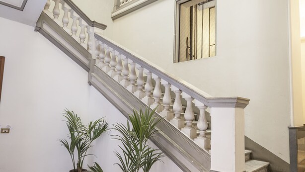 Una imponente escalera con barandillas blancas y suelo de mármol que lleva a un nivel superior.
