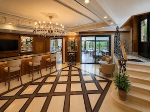 Un vestíbulo amplio con una zona de bar, un candelabro y una escalera que conduce a un piso superior.