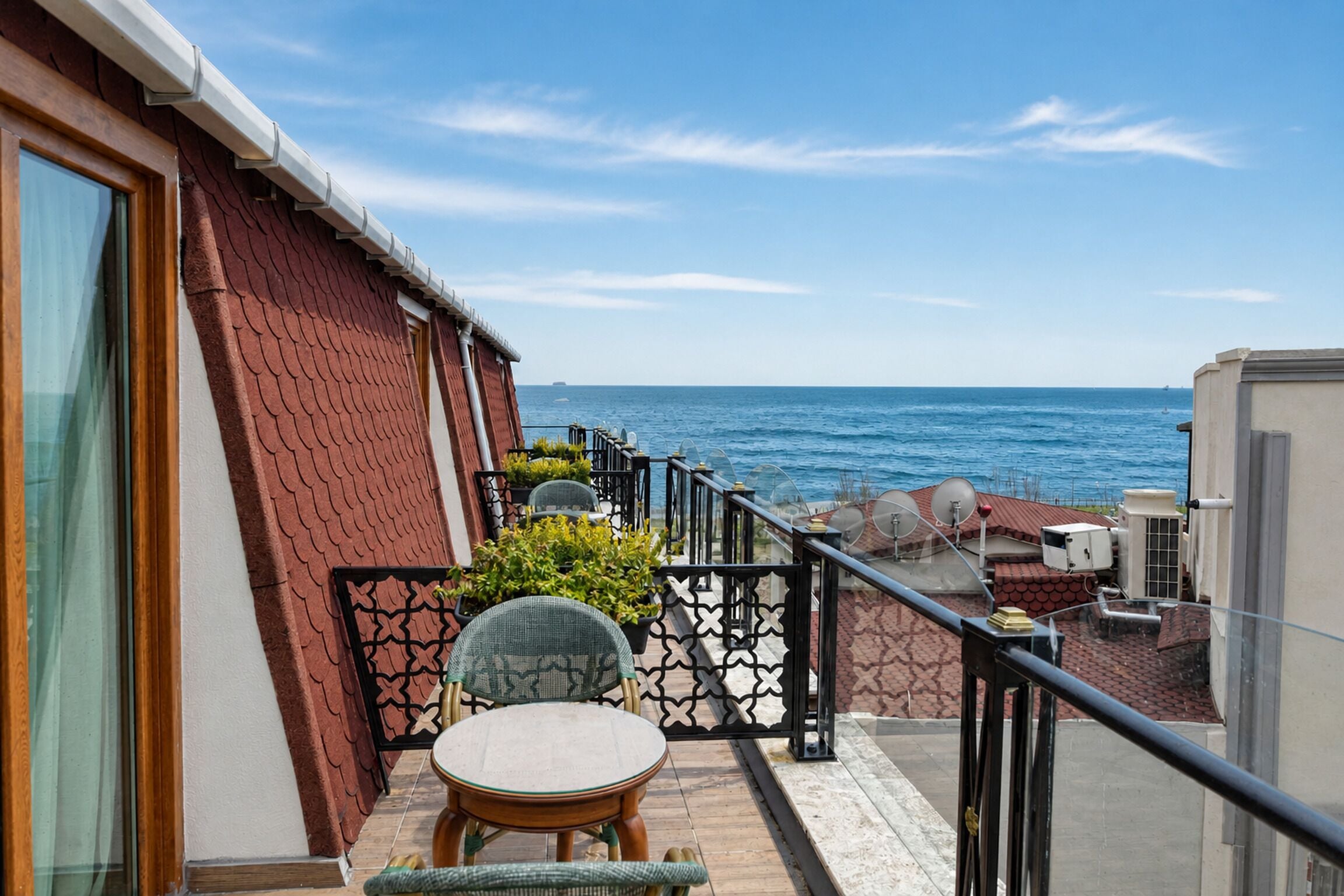 Un balcon avec vue sur la mer, une table avec des chaises et une rambarde.