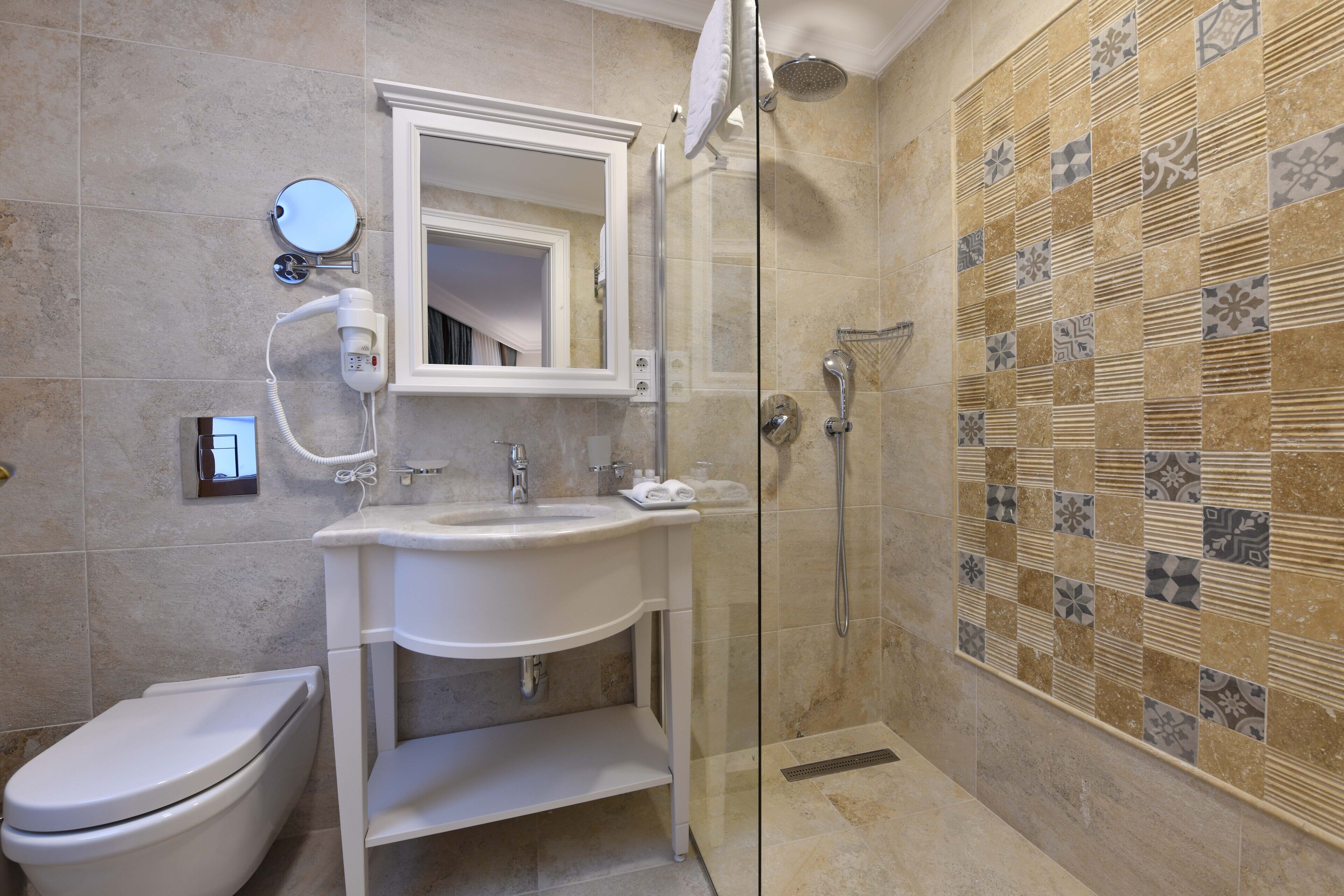 A bathroom with a toilet, sink, mirror, and shower.