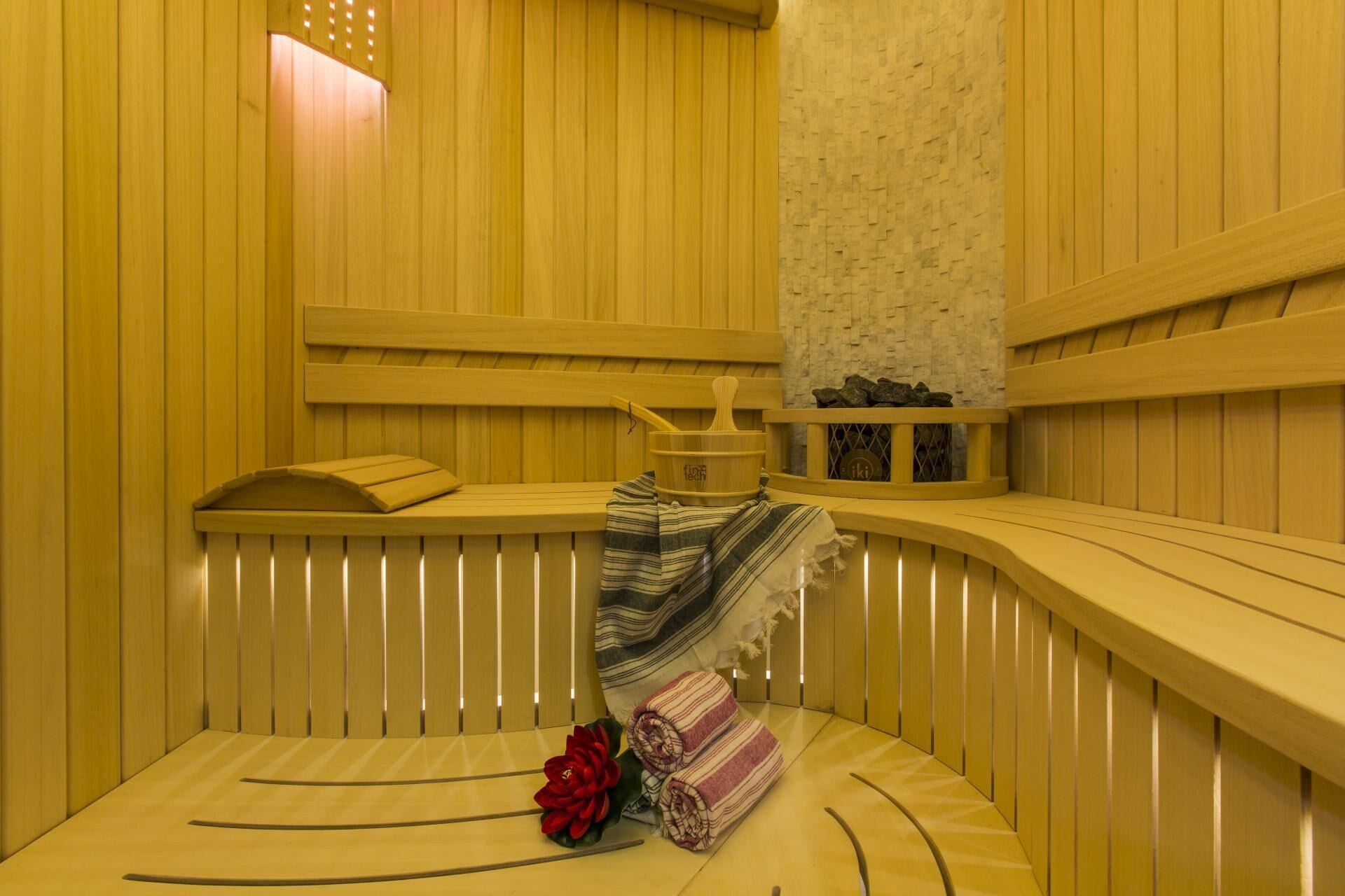 Un sauna avec des bancs en bois, un banc avec une serviette et une étagère en pierre.