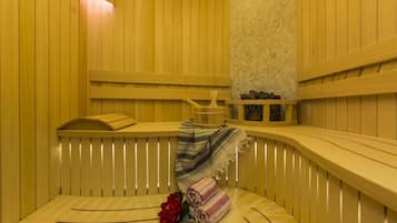 Un sauna avec des bancs en bois, un banc avec une serviette et une étagère en pierre.