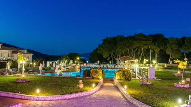 A nighttime resort with a swimming pool, outdoor seating, and a stone pathway. - Keri Village & Spa by Zante Plaza - Adults Only - All inclusive (Zakynthos)