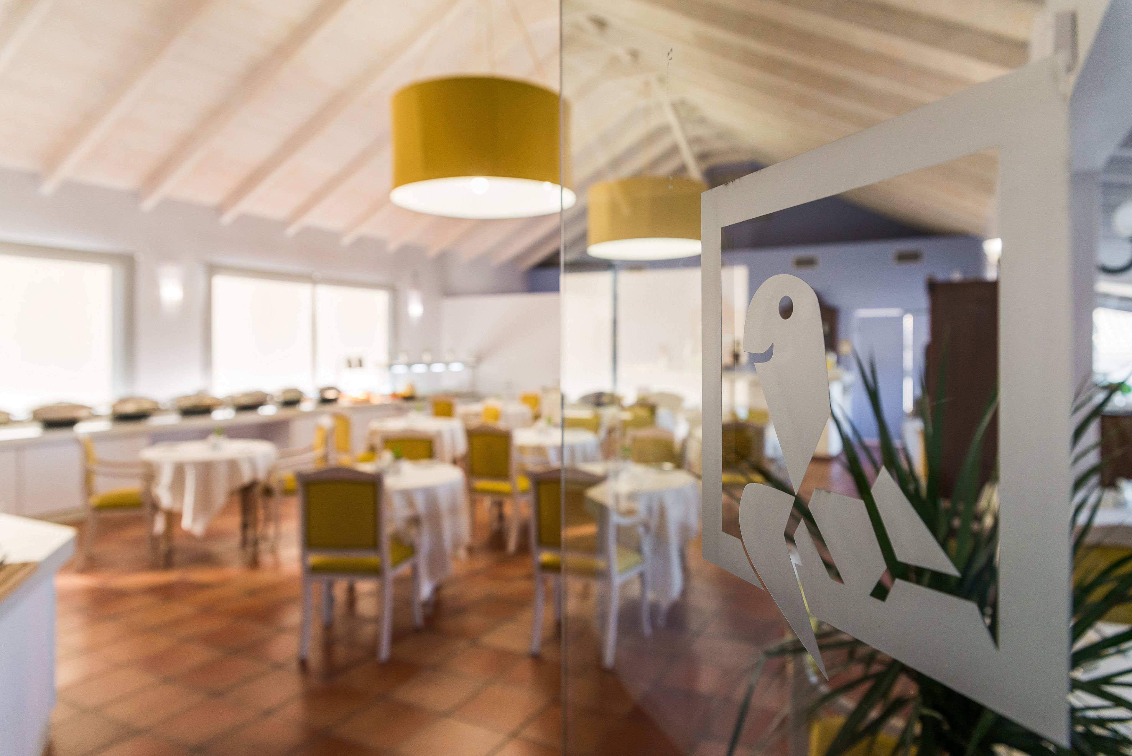 Un comedor con mesas redondas, sillas amarillas e iluminación colgante.