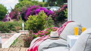 A garden view with a sofa, a hat, and two glasses of orange juice. - Keri Village & Spa by Zante Plaza - Adults Only - All inclusive (Zakynthos)