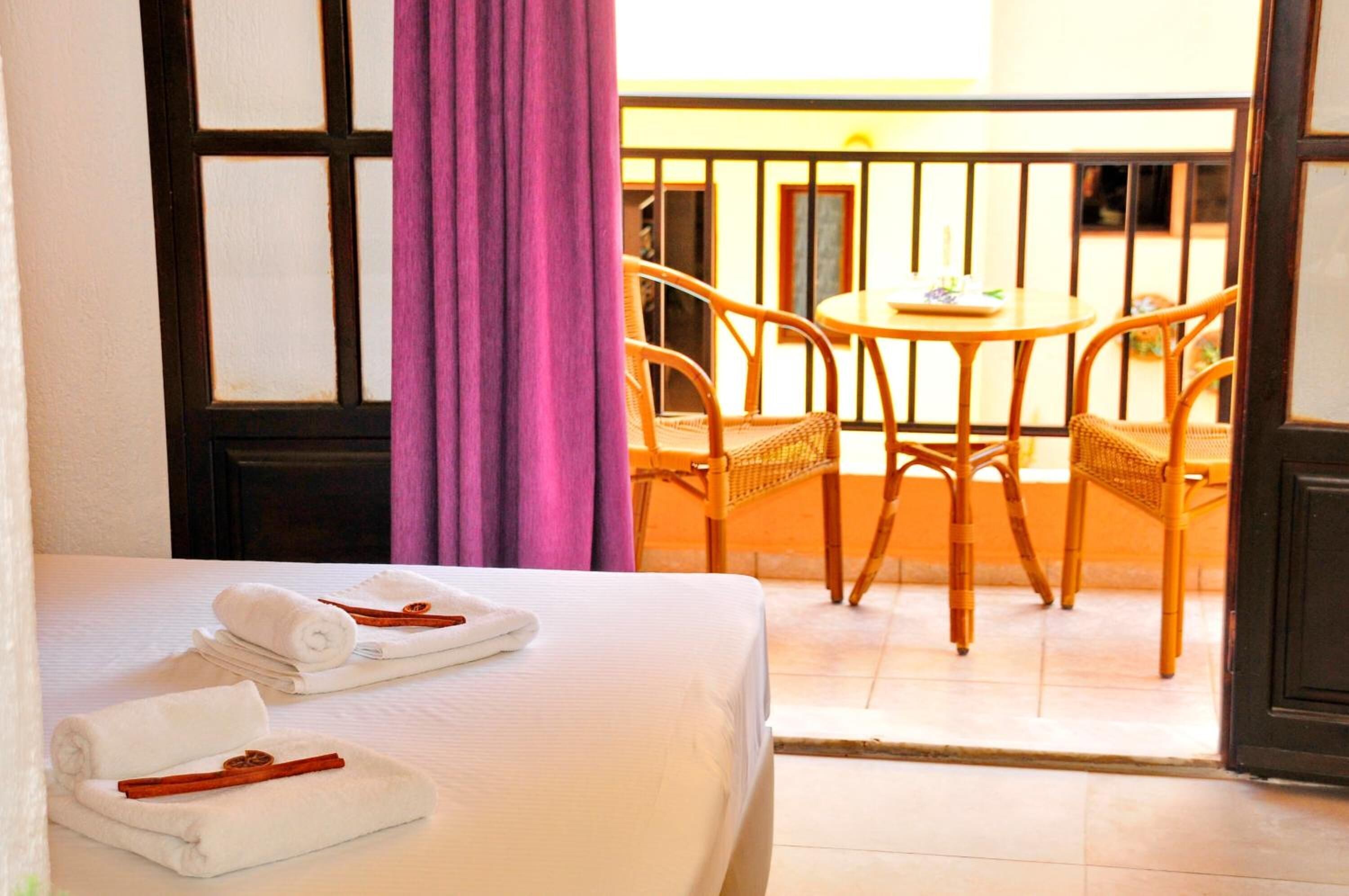 Una habitación de hotel con una cama, una mesa con sillas y un balcón con barandilla.