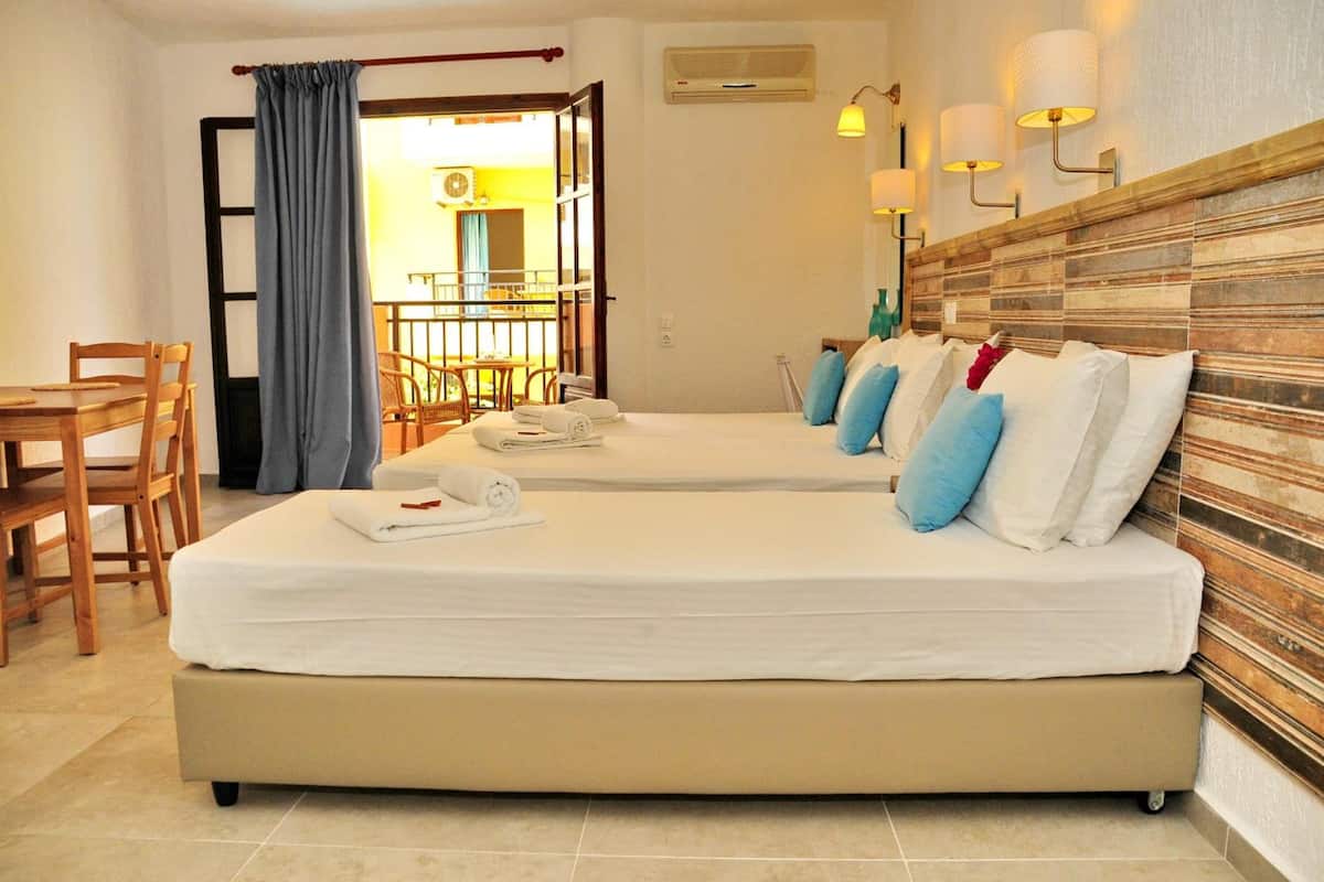 Habitación de hotel con dos camas, un comedor y vistas al exterior.