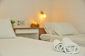A hotel room with two beds, white linens, a bedside table with a lamp, and a wall-mounted light. - Cleopatra Apartments (Hersonissos)