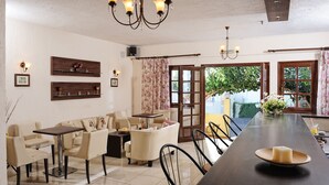 Comedor con una larga mesa, sillas, una lámpara de araña y vistas al exterior.