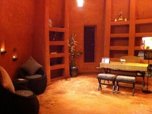 Una habitación acogedora con un banco de madera, una mesita pequeña y estantes con varios objetos.