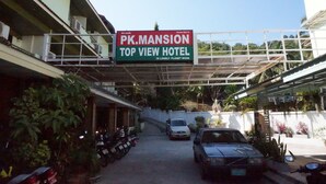 A sign for "PK. MANSION Top View Hotel" with a clear view of the entrance, parked cars, and surrounding greenery. - PK Mansion (Krabi)
