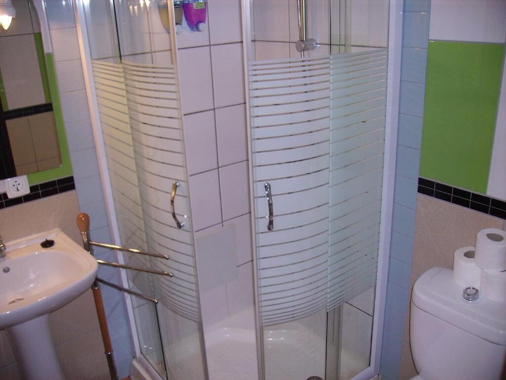 A bathroom with a glass shower enclosure, a sink, and a toilet.