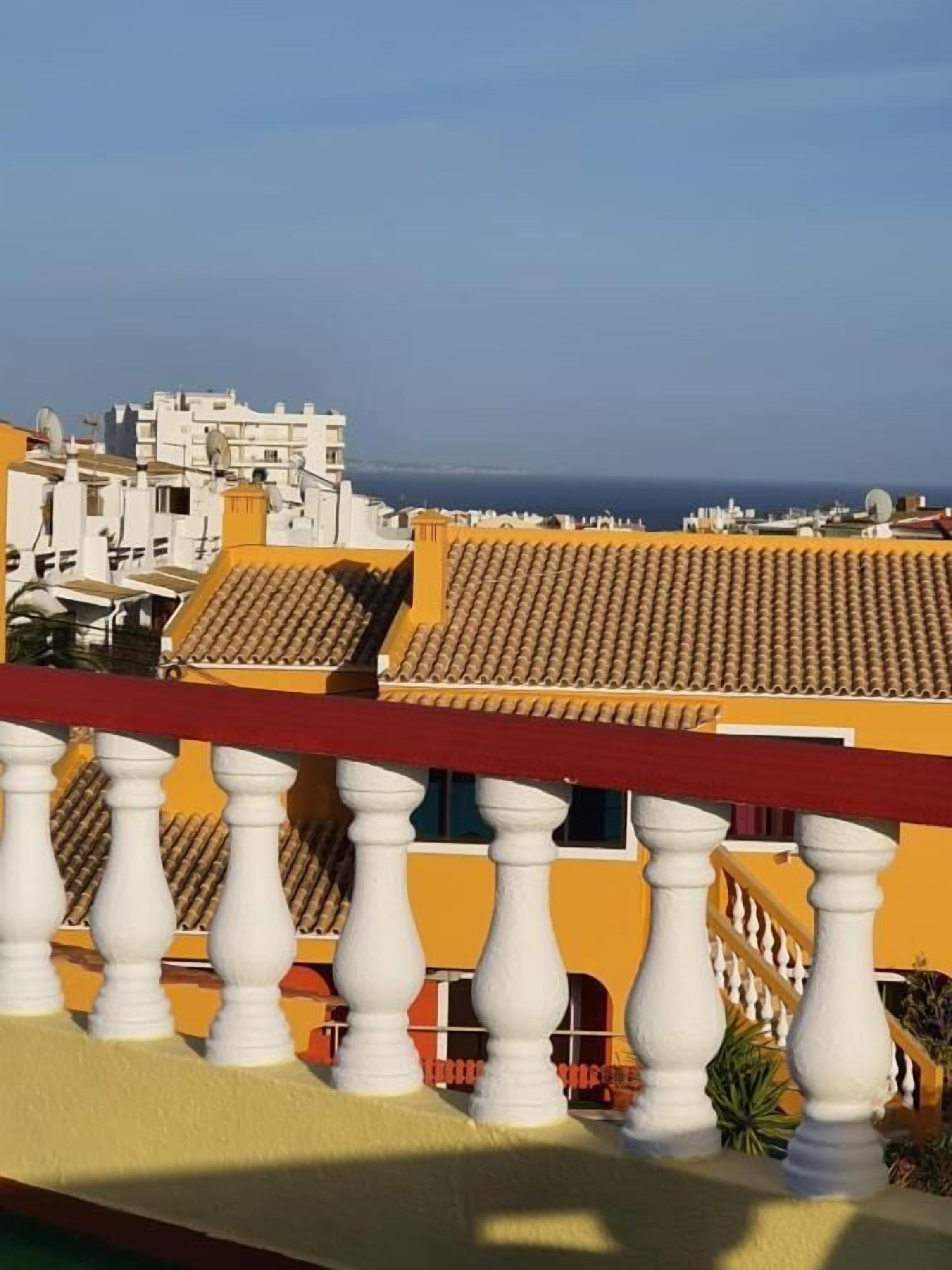 A yellow building with a tiled roof and white balustrades.