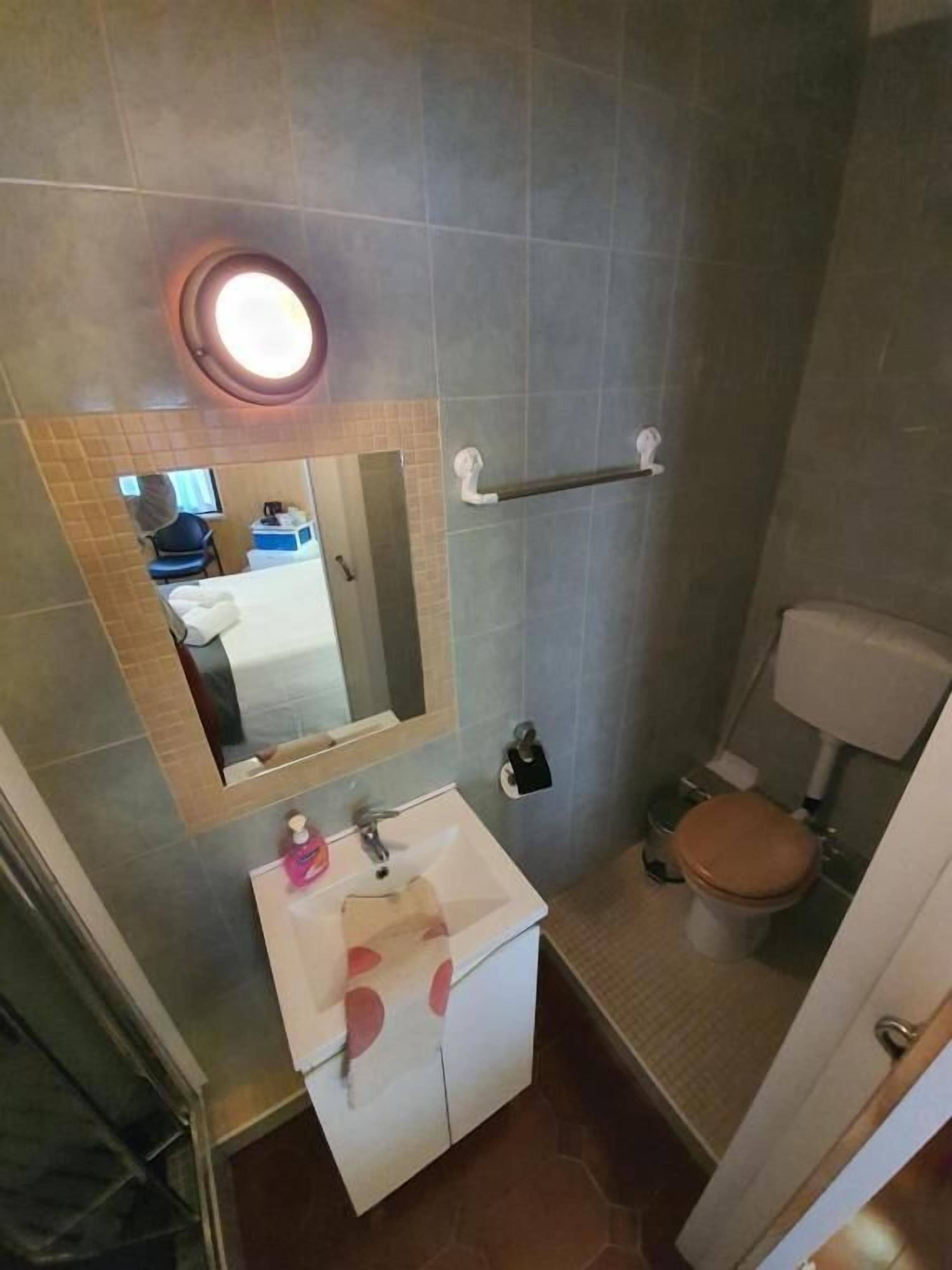 Un baño con lavamanos, espejo, inodoro y toallero.