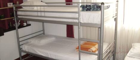 Une chambre avec un lit superposé, une étagère et une fenêtre.