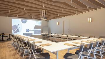 A conference room with a long table, chairs, a projector screen, and a whiteboard.