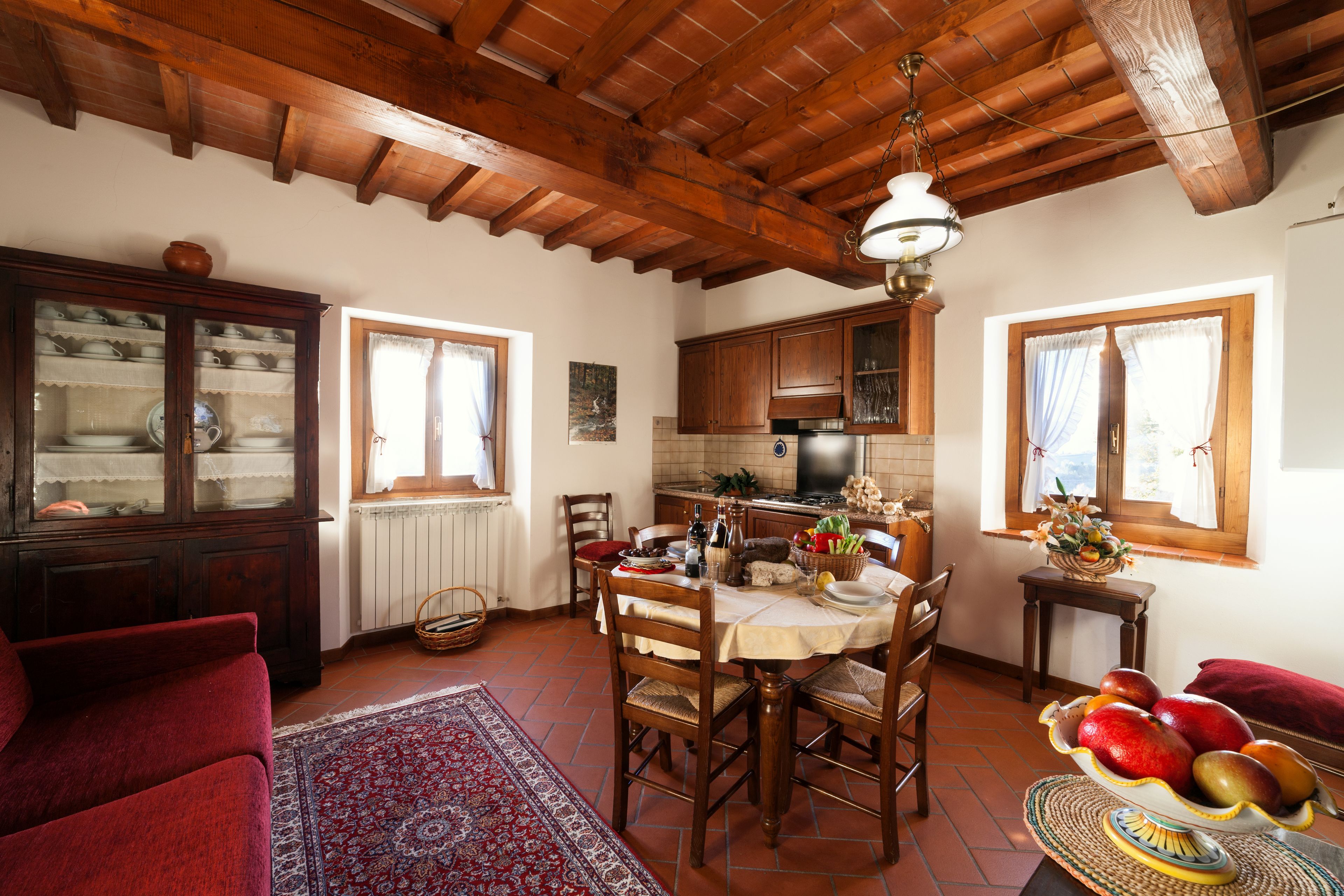 A cozy dining area with wooden furniture, a tiled floor, and a red sofa.