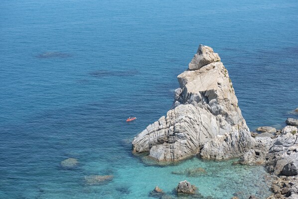 Costa rocosa con agua azul cristalina y un pequeño bote.