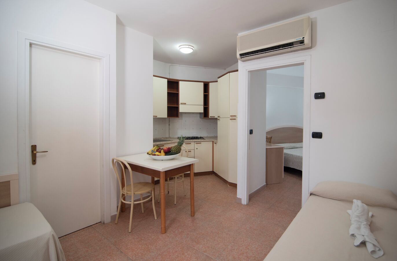 Une pièce compacte comprenant un coin cuisine, un espace repas avec une table et des chaises, et un lit.