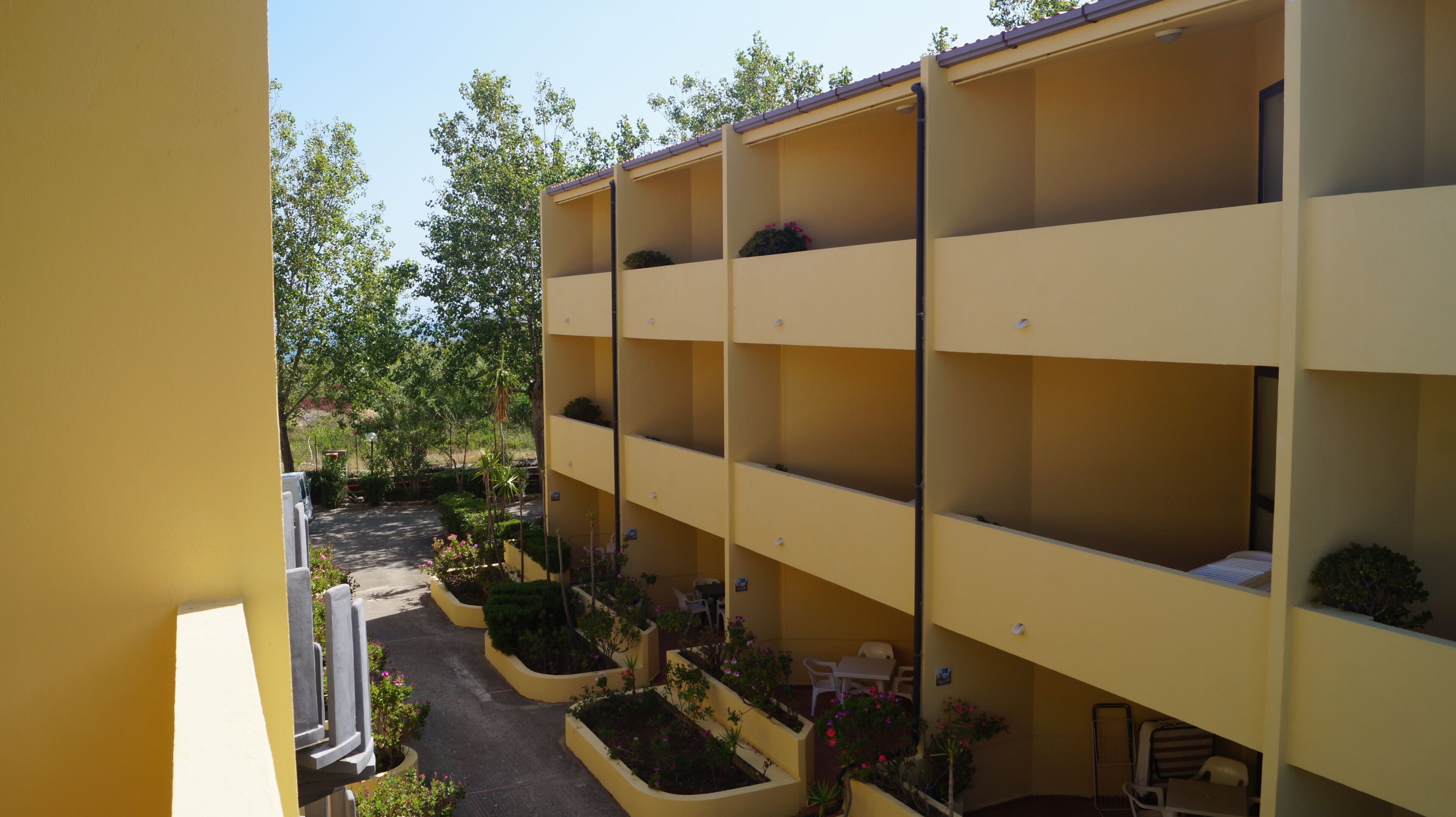 Un edificio a più piani con balconi, posti a sedere all'aperto e fioriere.