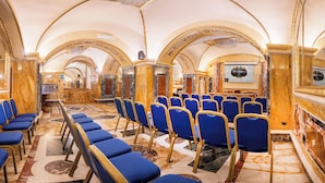Un hall d’hôtel luxueux, avec un sol en marbre, des chaises bleues et des décorations dorées élaborées.