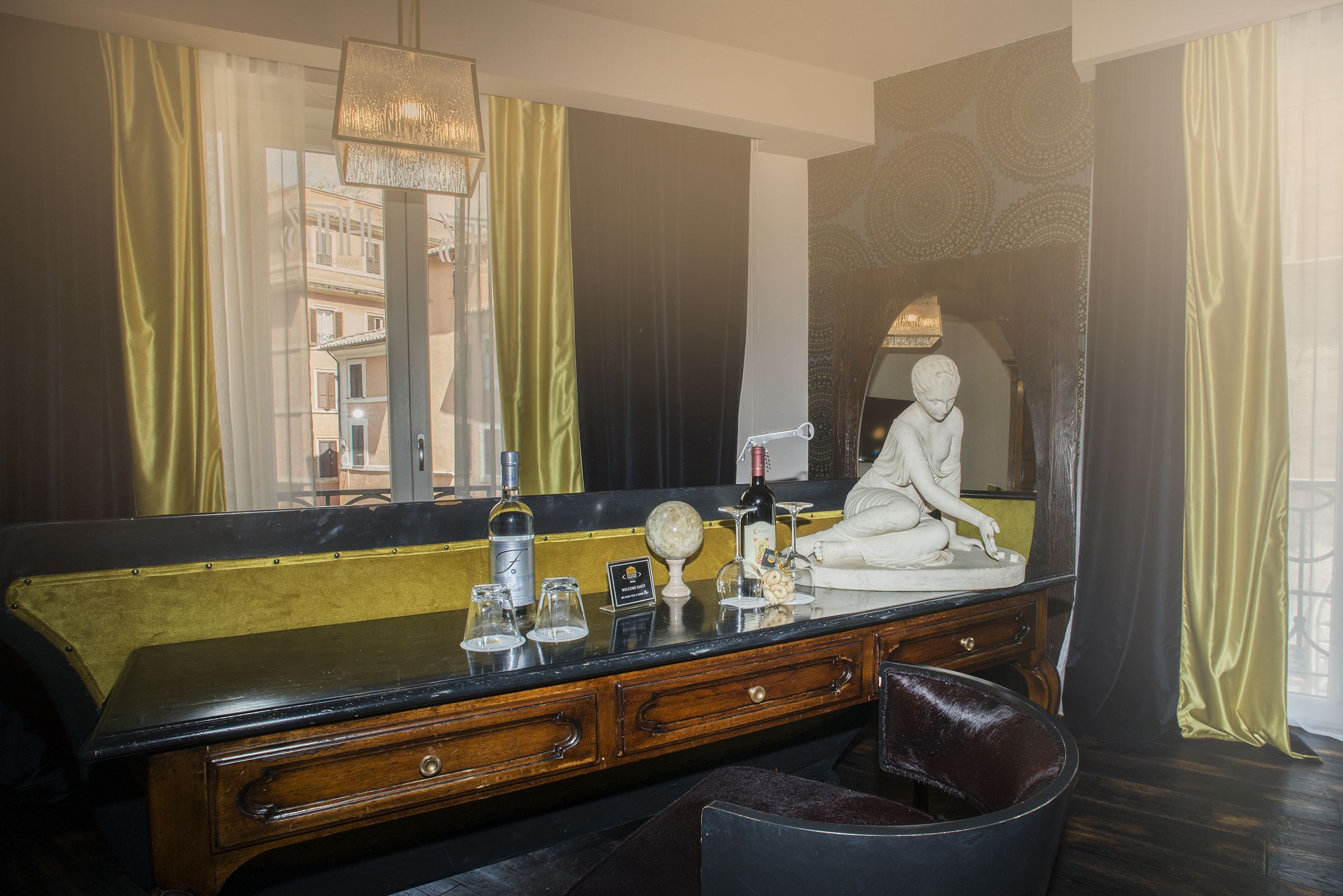 Una habitación con un espejo grande, una estatua y un escritorio con varios objetos.