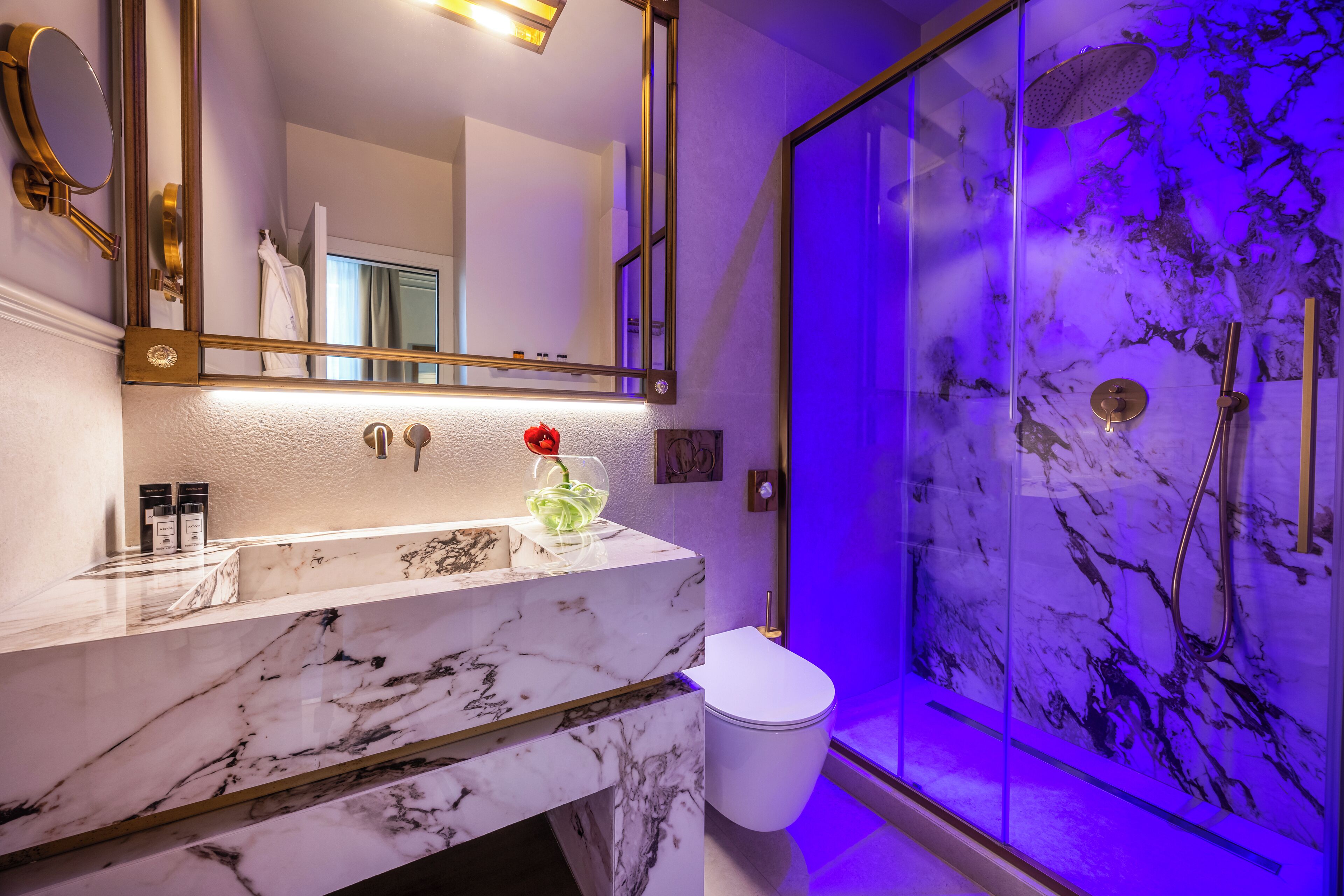 A bathroom with a marble vanity, a glass shower enclosure, and a large mirror.