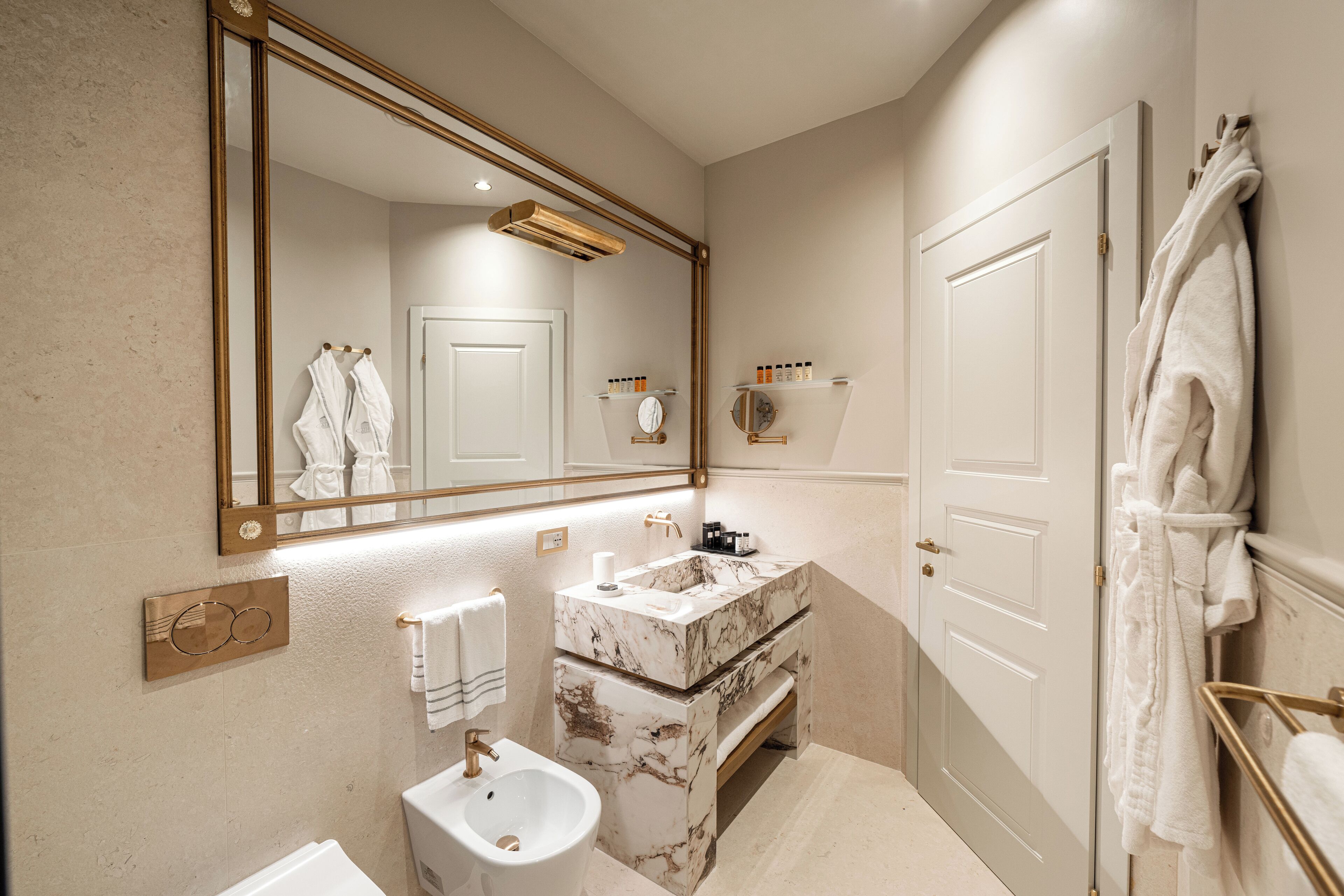 A bathroom with a marble sink, a large mirror, and a towel rack.