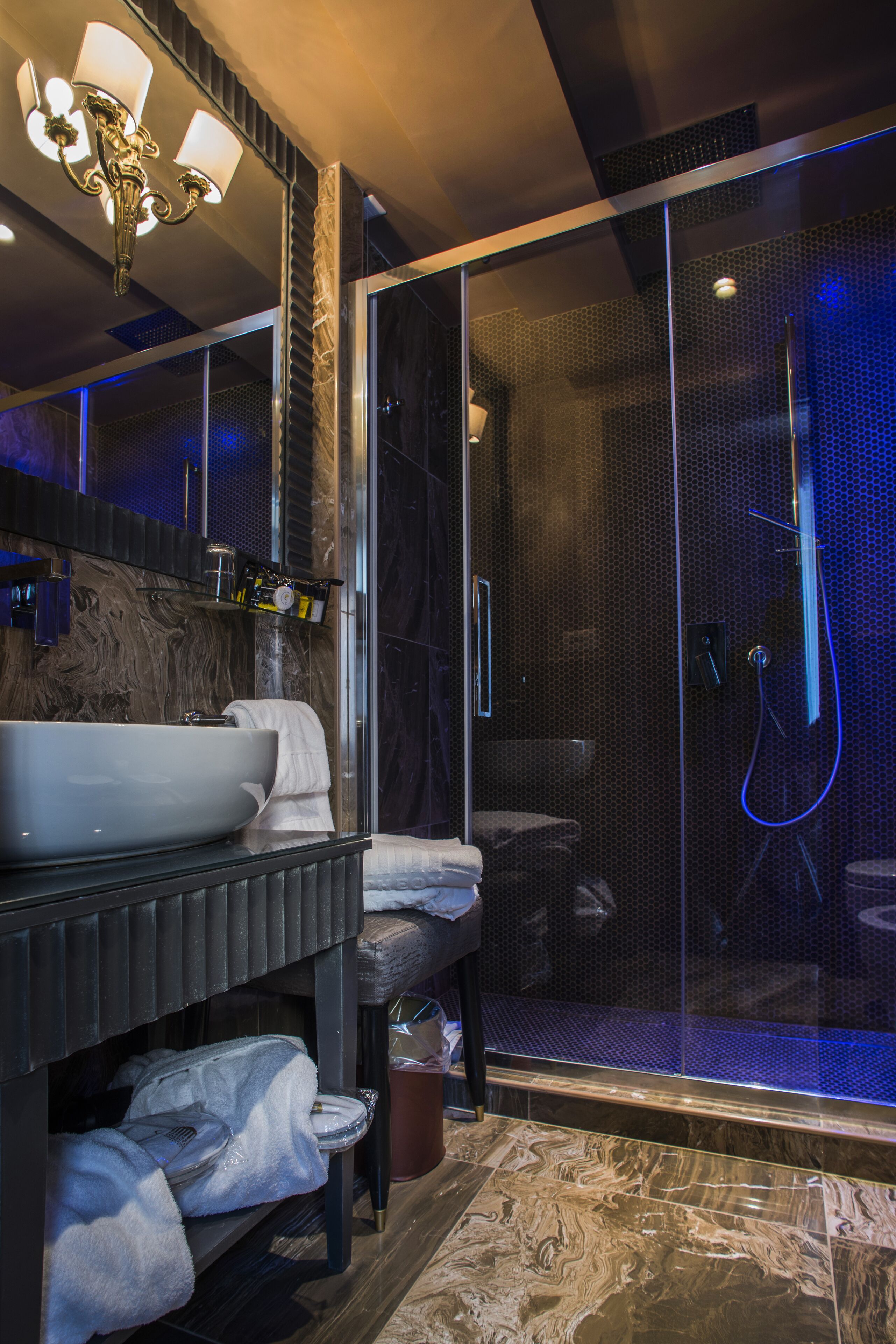 Un baño moderno con un lavamanos grande, cabina de ducha con mampara de vidrio y un perchero para toallas.