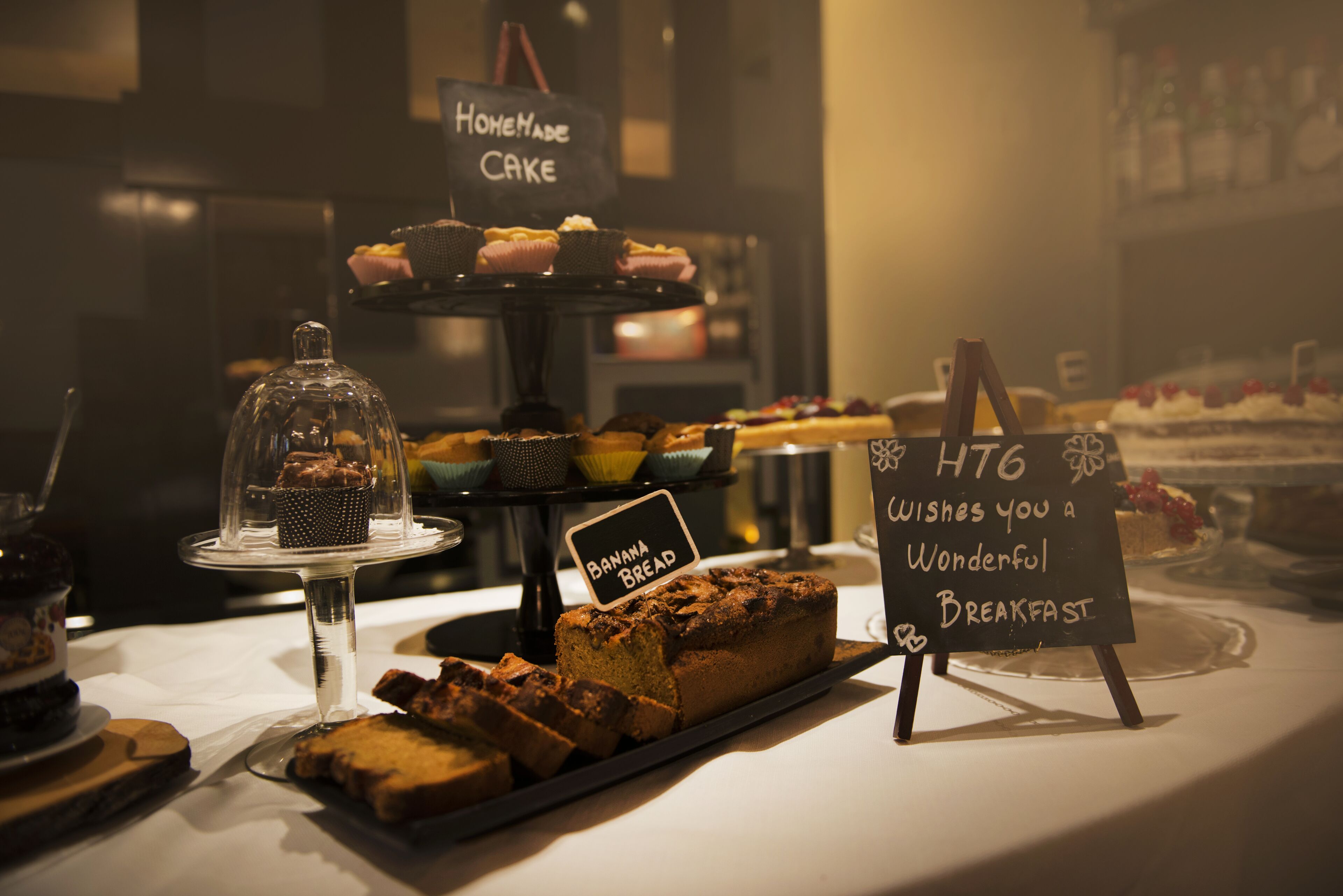 Un bufé de desayuno con diversos productos de panadería y un letrero que dice "HTG WISHES YOU A WONDERFUL BREAKFAST".
