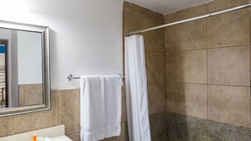 Un baño con inodoro, lavabo, espejo y ducha.