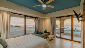 Ein Schlafzimmer mit Bett, Sofa, Deckenventilator und Blick auf den Strand.