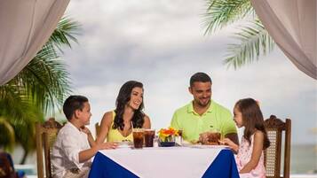 Una familia cenando en una mesa con vista al océano.