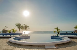 Une piscine avec vue sur l’océan et les palmiers.