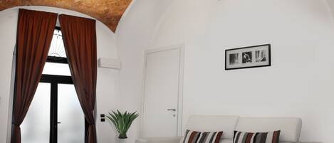 A modern living room with a white sofa, a small table, and a potted plant.