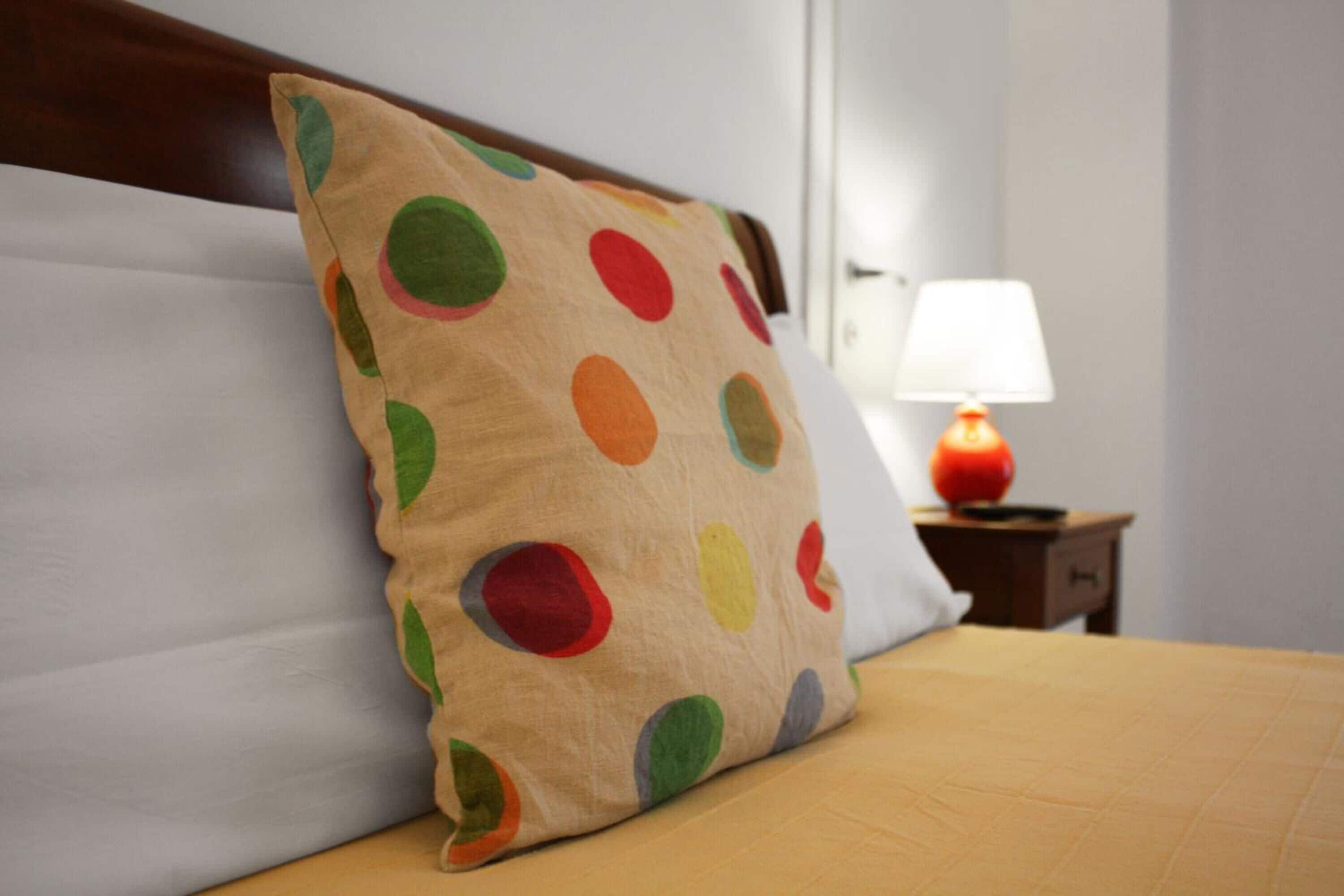 A bed with a polka dot pillow and a nightstand with a lamp.