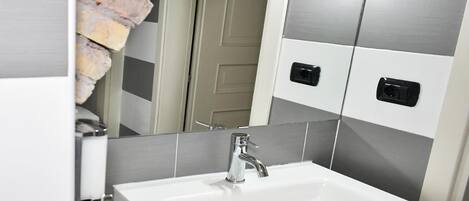A bathroom with a white sink, a mirror, and a towel rack.