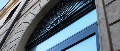 A reception area with a sign above a glass door, part of a building with stone facade and arched window design.