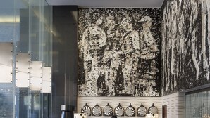 Un lobby moderno con un hombre de pie, una mesa de recepción y zonas de estar.