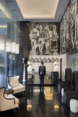A modern lobby with a man standing, a reception desk, and seating areas. - DaVinci Suites (Sandton)
