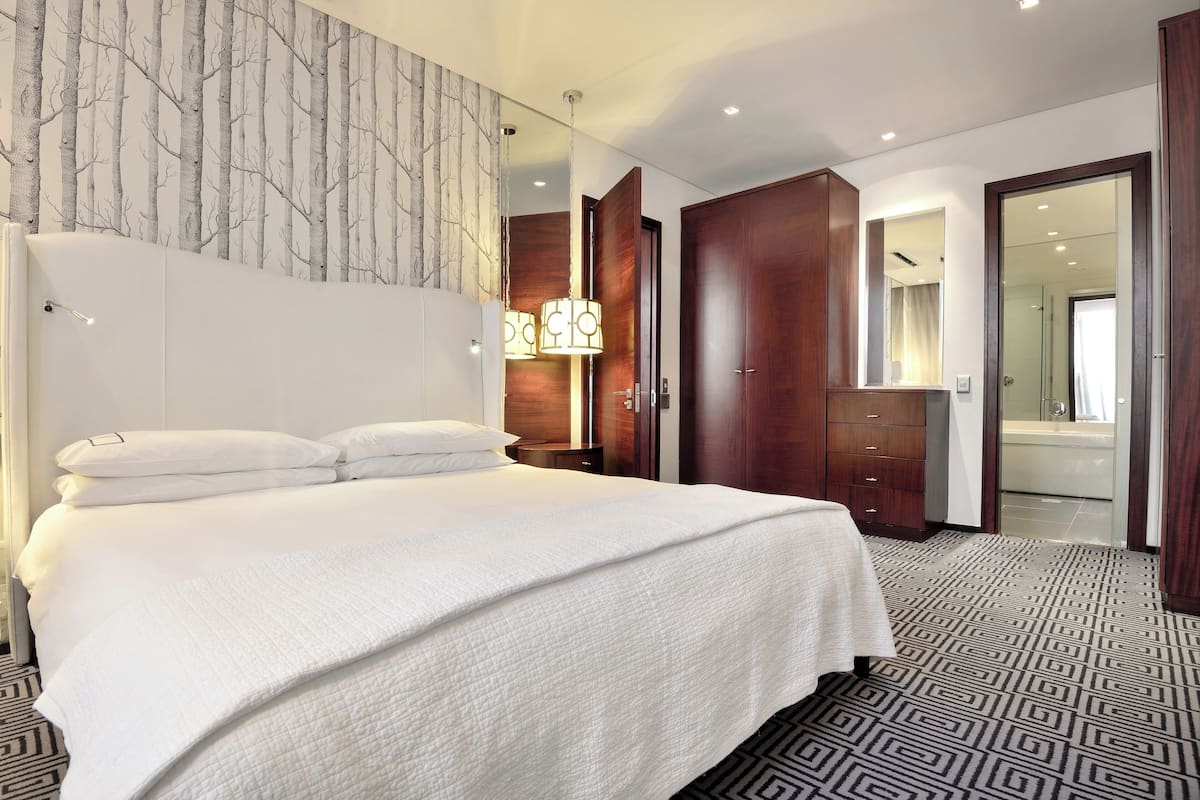 Een moderne hotelkamer met een groot bed, een garderobe en een badkamer die door een open deur zichtbaar is.
