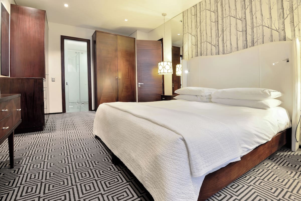 Een hotelkamer met een groot bed, een kledingkast, een spiegel en een vloer met een patroon.