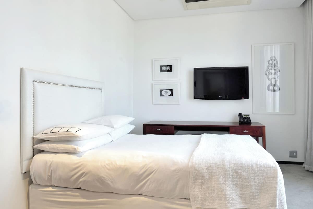 Een moderne hotelkamer met een groot bed, een flatscreen-tv aan de wand, een bureau met telefoon en een ingelijste foto.
