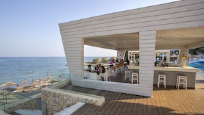 A modern outdoor dining area with a poolside bar, overlooking the sea. - Sunrise Hotel (Rhodes)