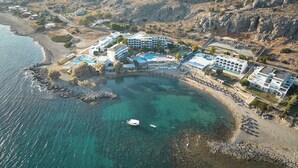 An aerial view of a coastal resort with multiple buildings, a swimming pool, and a beach. - Sunrise Hotel (Rhodes)
