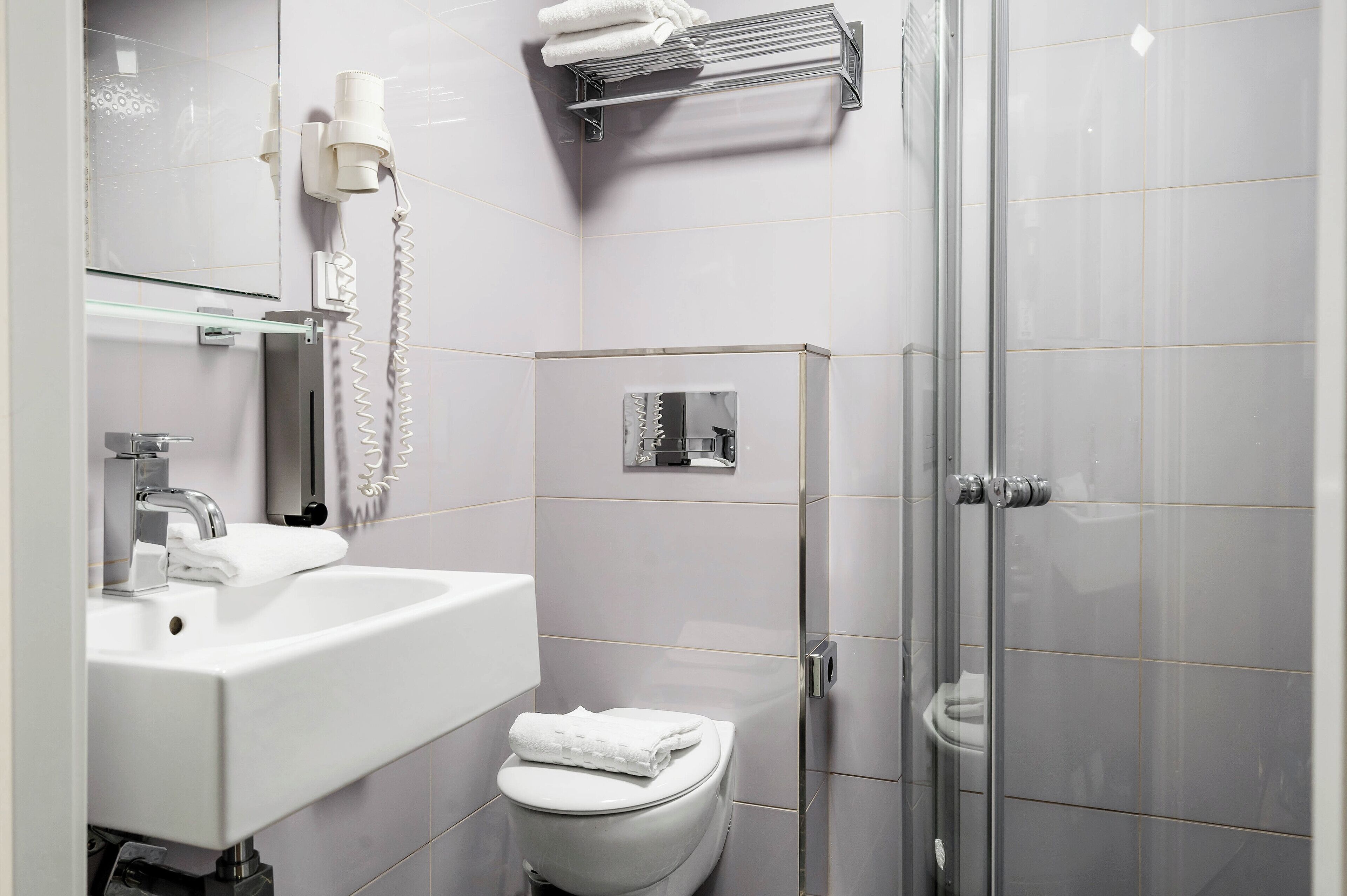 Un baño moderno con lavamanos, inodoro y ducha blancos.
