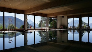 Une grande piscine intérieure offrant une vue dégagée sur les montagnes grâce à de larges baies vitrées.