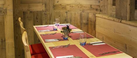 Un comedor de madera con una decoración de pared en forma de estrella, bancos acolchados rojos y una mesa preparada para cuatro personas.