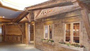 Un bâtiment rustique en bois, doté de grandes fenêtres et d’un motif géométrique sur le sol.