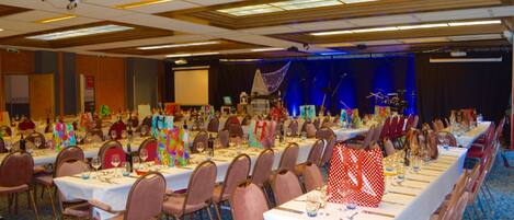 A banquet hall with long tables set for dining, equipped with chairs and table settings.